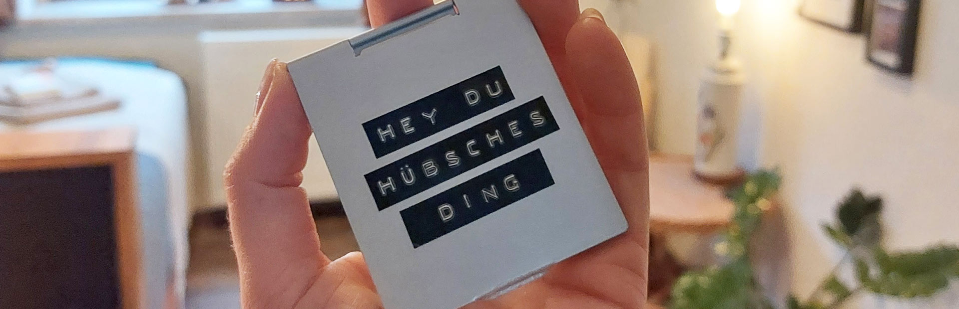 Eine Hand hält ein kleines Schild mit der Aufschrift Hey du hübsches Ding